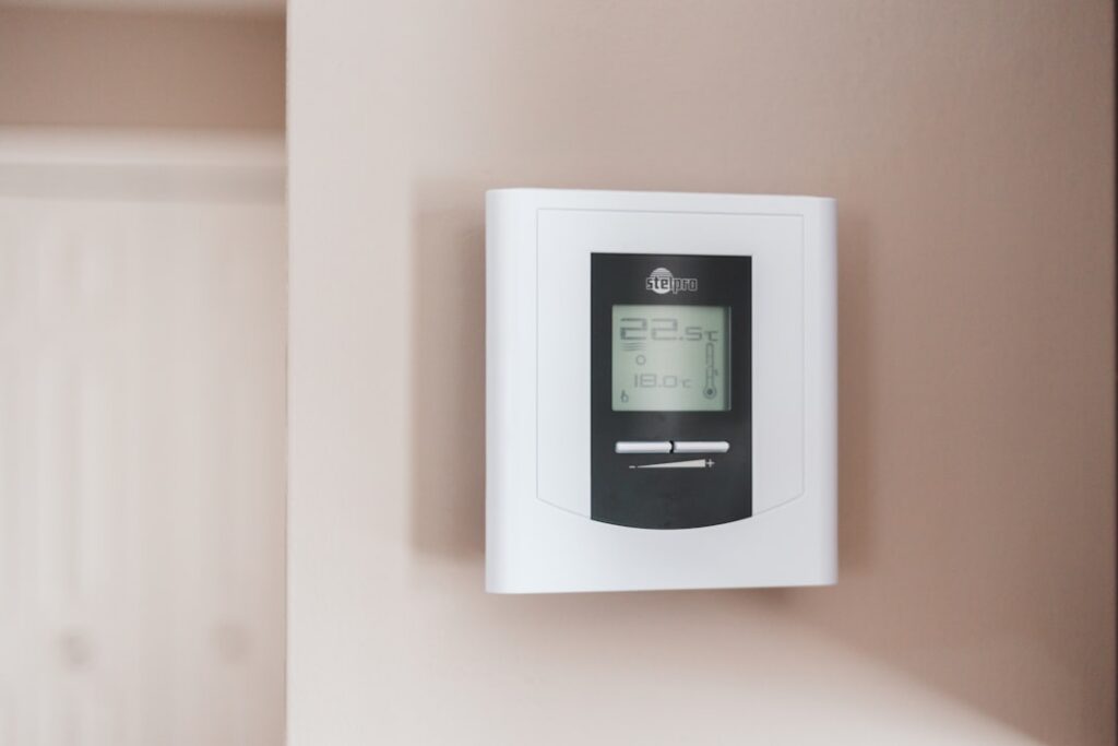 modern home thermostat on wall with comfortable living room in background